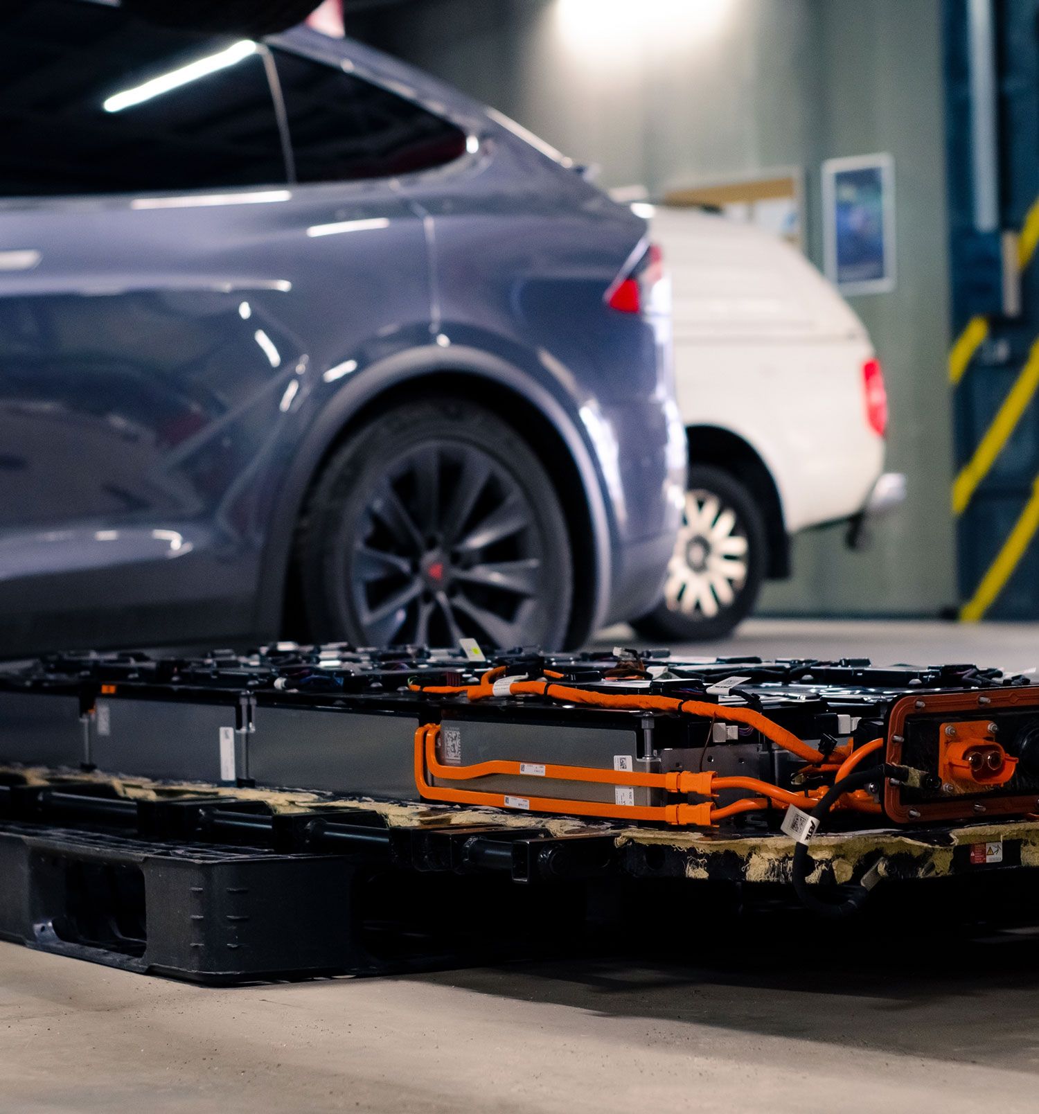 Tesla Model X next to an electric vehicle battery pack on the shop floor