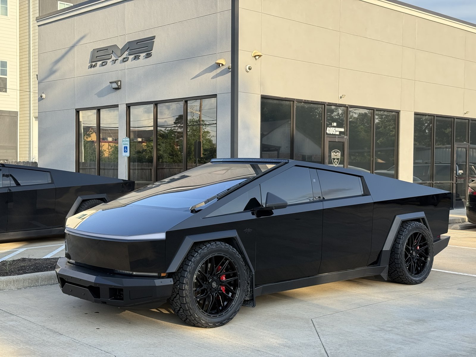 Gloss black Cybertruck with armor bumper and roof light bar at EVS Motors Houston