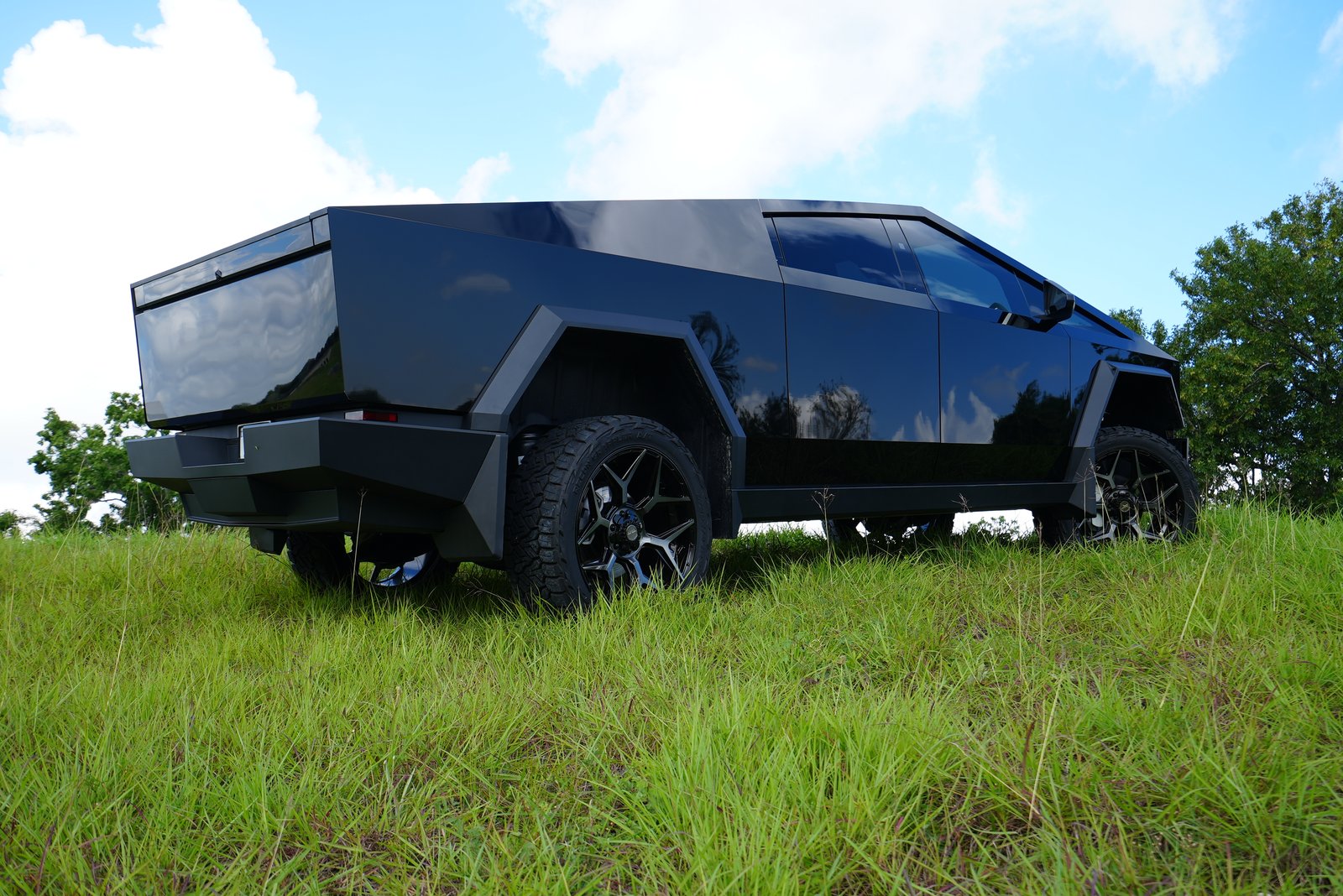 Gloss black Cybertruck rear view in field