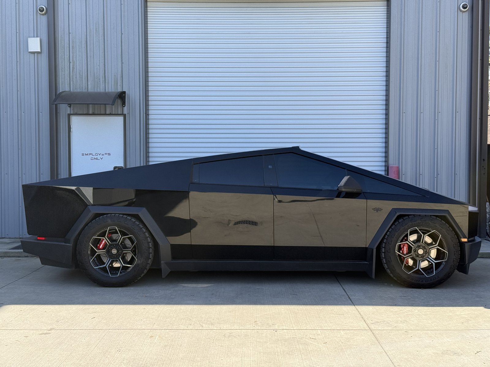 Gloss black Cybertruck with hexagonal wheels and red calipers in garage
