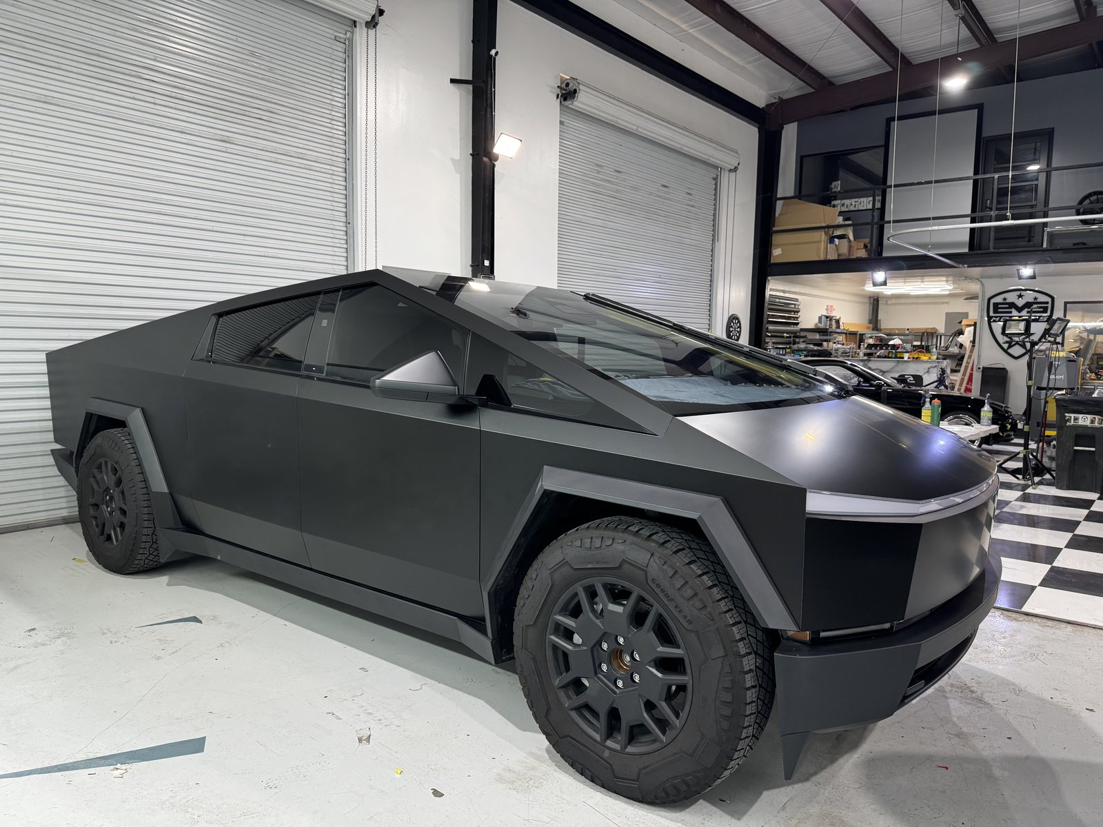 Matte black Cybertruck in shop with EVS sign