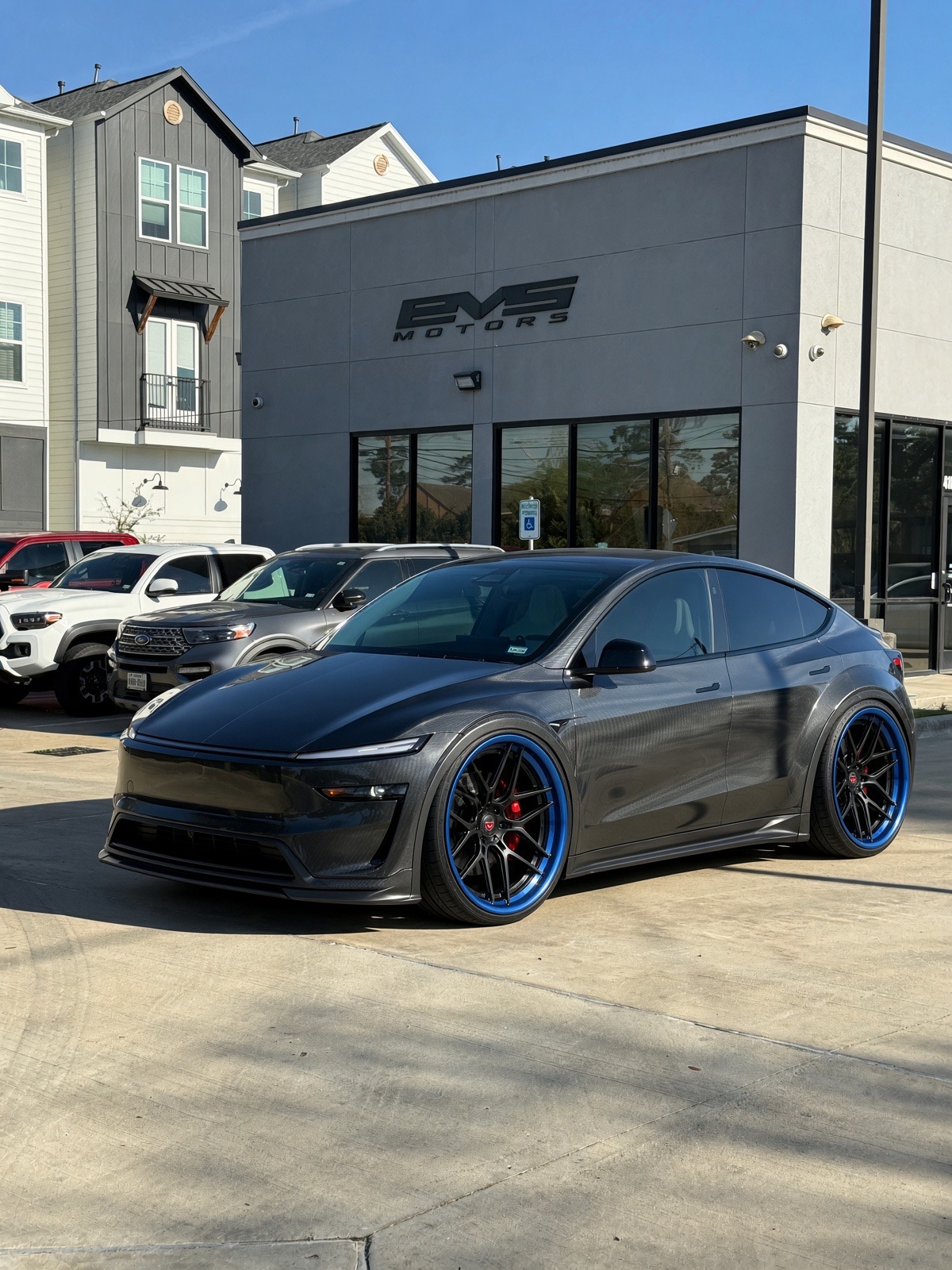 Carbon-fiber widebody Tesla Model Y Juniper on custom forged wheels parked in front of EVS Motors in Houston