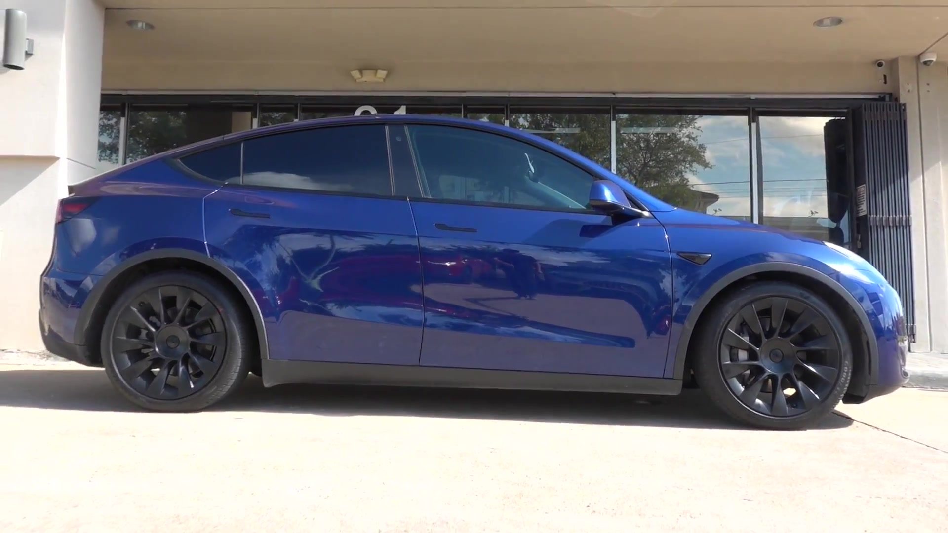 Blue Tesla Model Y sitting lower on Öhlins coilovers outside EVS Motors