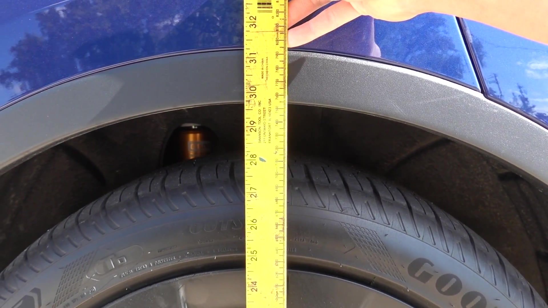 Tape measure at the fender of a Tesla Model Y, checking wheel gap