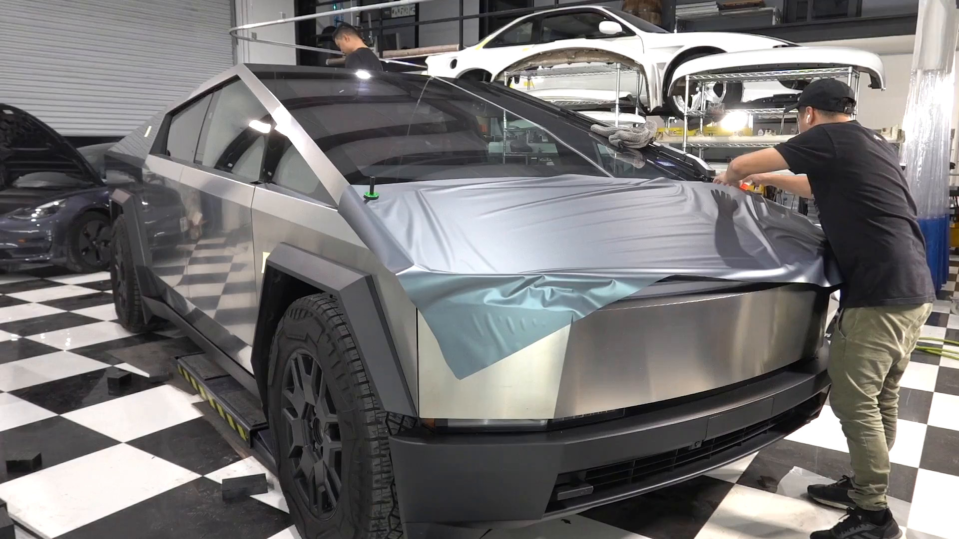 EVS Motors installer wrapping a Tesla Cybertruck in matte blue vinyl