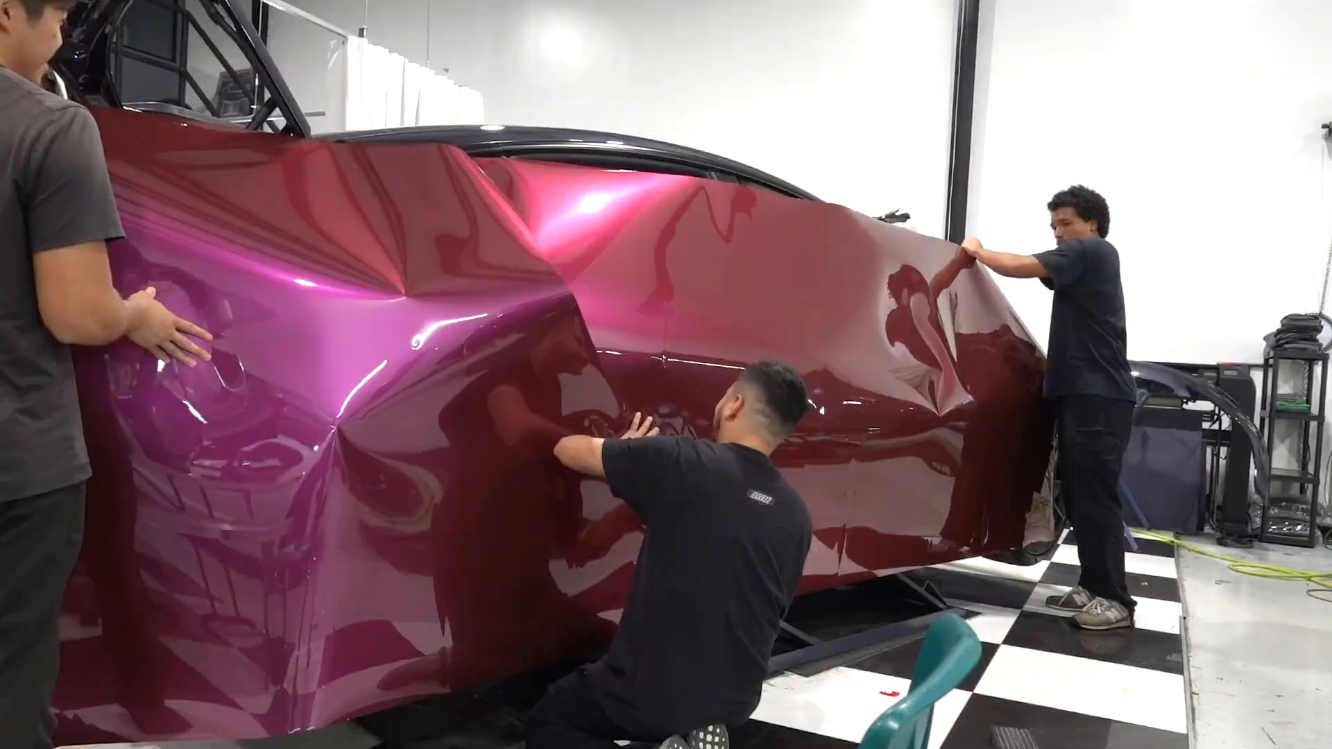 EVS Motors team wrapping a Tesla Model 3 in pink Inozetek vinyl